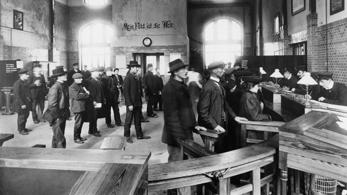 Menschen stehen in Schlangen an Ticketschaltern im Hamburger Hafen, alte Schwarzweiß-Aufnahme.