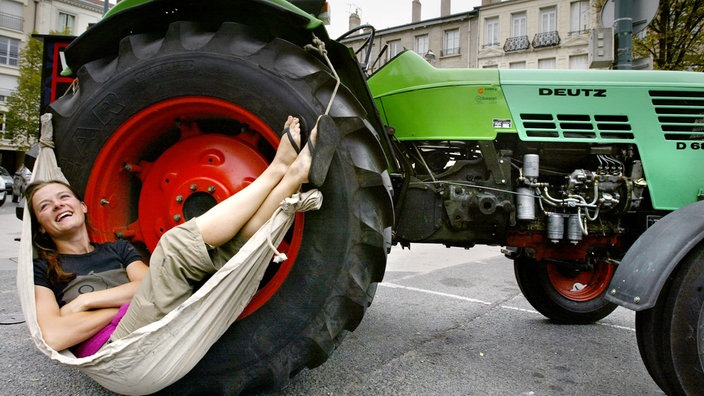 Eine Frau liegt in einer Hängematte, die an einem Traktor festgemacht ist.