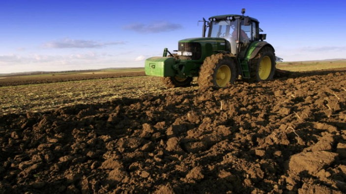 Landwirt pflügt Acker mit einem Traktor um.