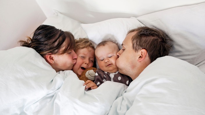 Eine Familie liegt im Bett.