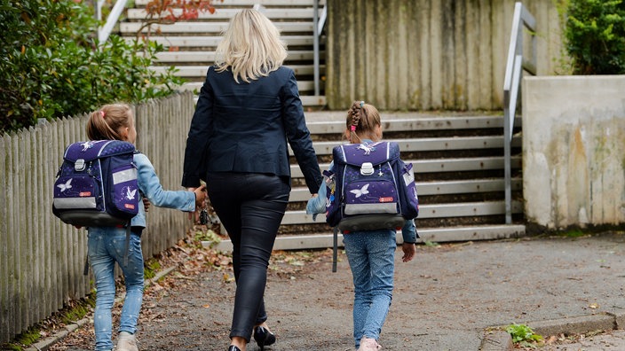 Zwillingsmädchen mit ihrer Mutter auf dem Weg zur Schule