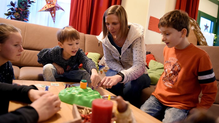 Eine Knderdorfmutter spielt mit Kindern ein Gesellschaftsspiel