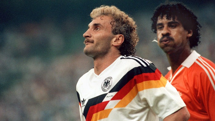 Hinter Rudi Völler geht Frank Rijkaard vorbei. Rijkaard spuckt Völler in den Nacken, dieser bemerkt zunächst nichts von der Attacke.