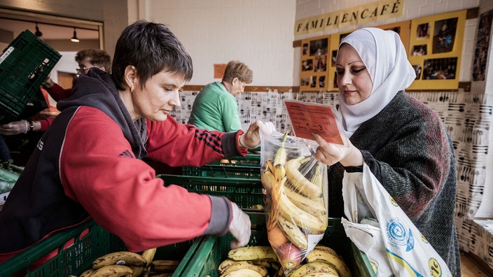 Eine Kundin wird von einer Helferin der Tafel bedient