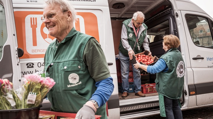 Helfer der Tafel laden einen Bus voller Lebensmittel aus