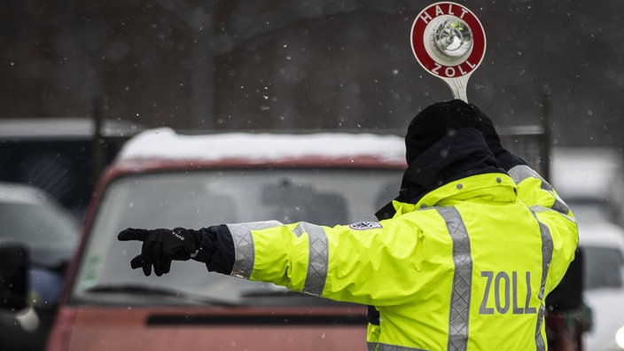 Ein Zollmitarbeiter hält ein Auto zur Zollkontrolle an