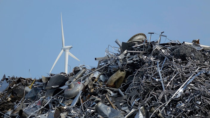 Berg von Altmetall vor einem Windrad