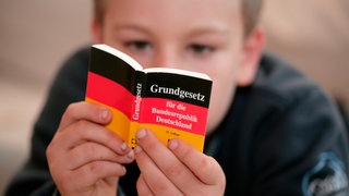 Ein Kind liest im Grundgesetz