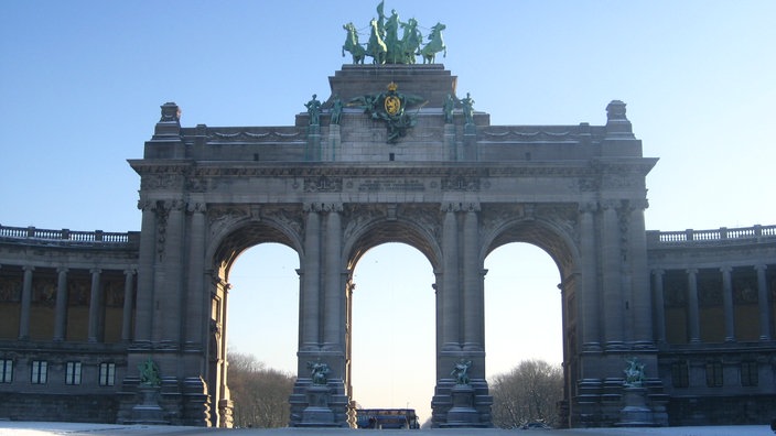 Groß und grau ragt der Triumphbogen empor. Auf ihm thront eine Quadriga.