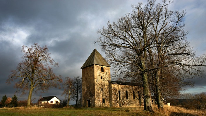 Kirchenruine vor wolkenverhangenem Himmel.