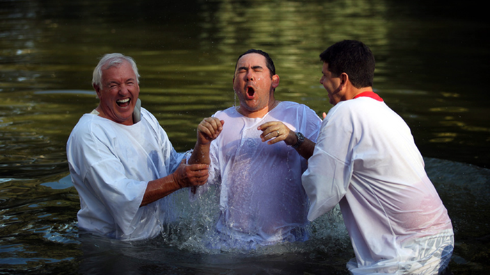 Ein junger Mann wird im Fluss getauft.