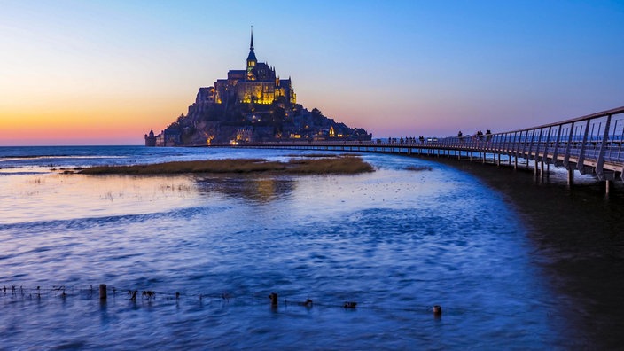 Der Mont St. Michel mitsamt seiner Brücke im Abendlicht