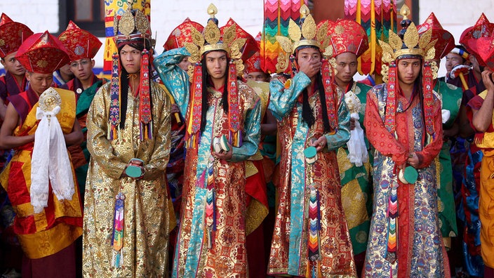 Vier buddhistische Mönche in festlichen, reich verzierten Trachten.