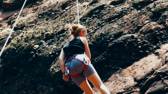 Eine Frau seilt sich am Berg ab.