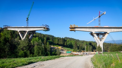 Brücke in der Mitte nicht fertig mit Kränen auf beiden Seiten in Naturgebiet über Schotterstraße