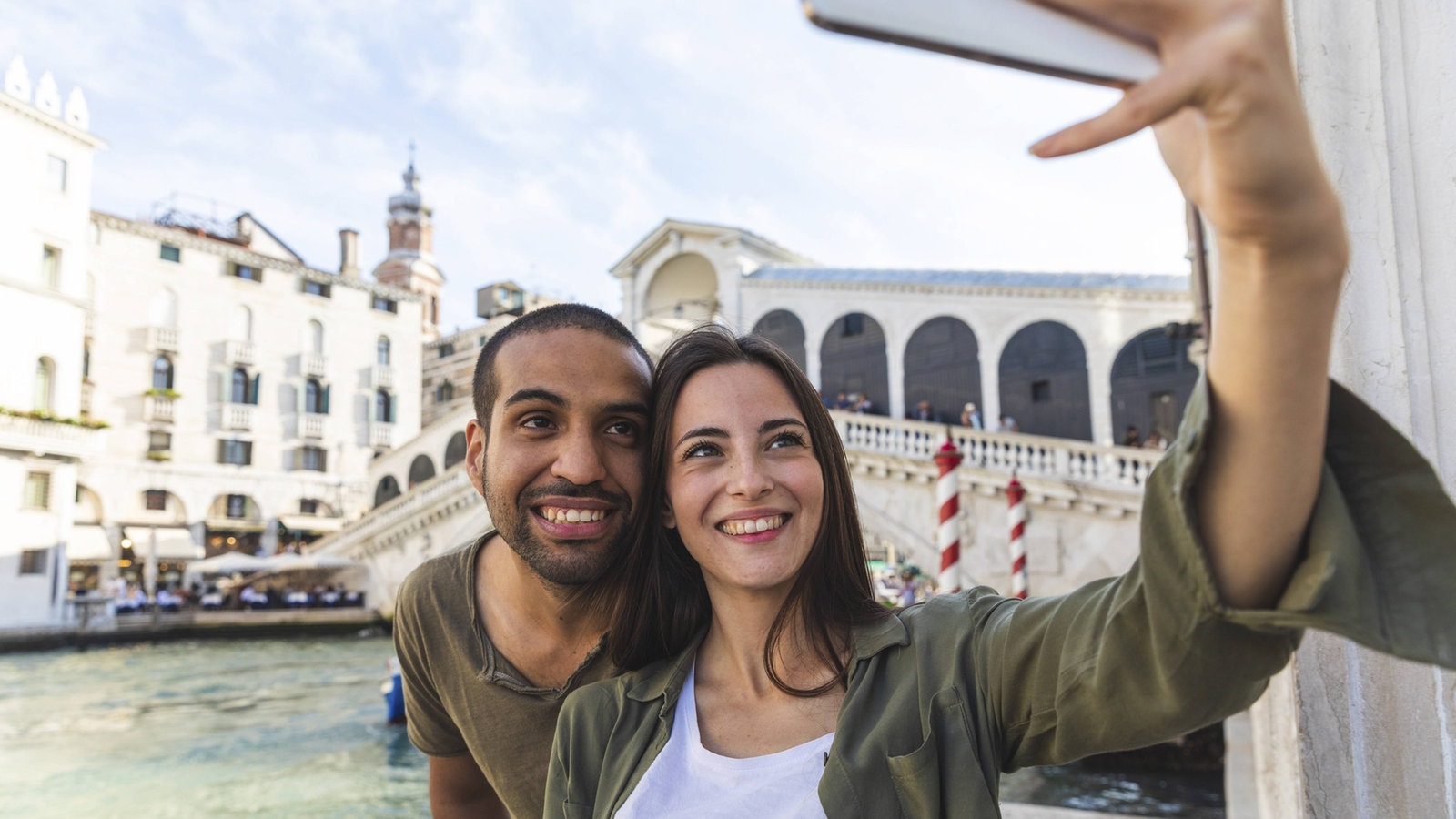 Eine Frau und ein Mann machen ein Selfie vor der Rialtobrücke in Venedig