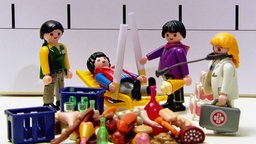 Playmobil-Männchen stehen vor einer Zeitskala. Um sie herum: Alkohol und Zigaretten.