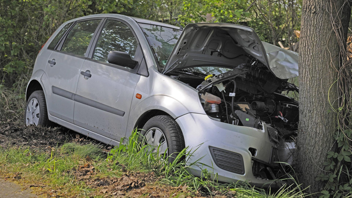 Ein Auto mit zerstörtem Vorderteil liegt in einem Seitengraben vor einem Baum